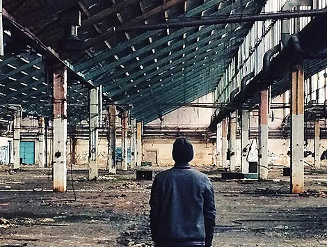 A rear view of a man standing in an abandoned factory